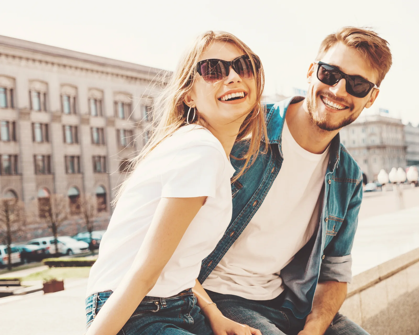 Smiling couple wearing sunglasses on a city sidewalk