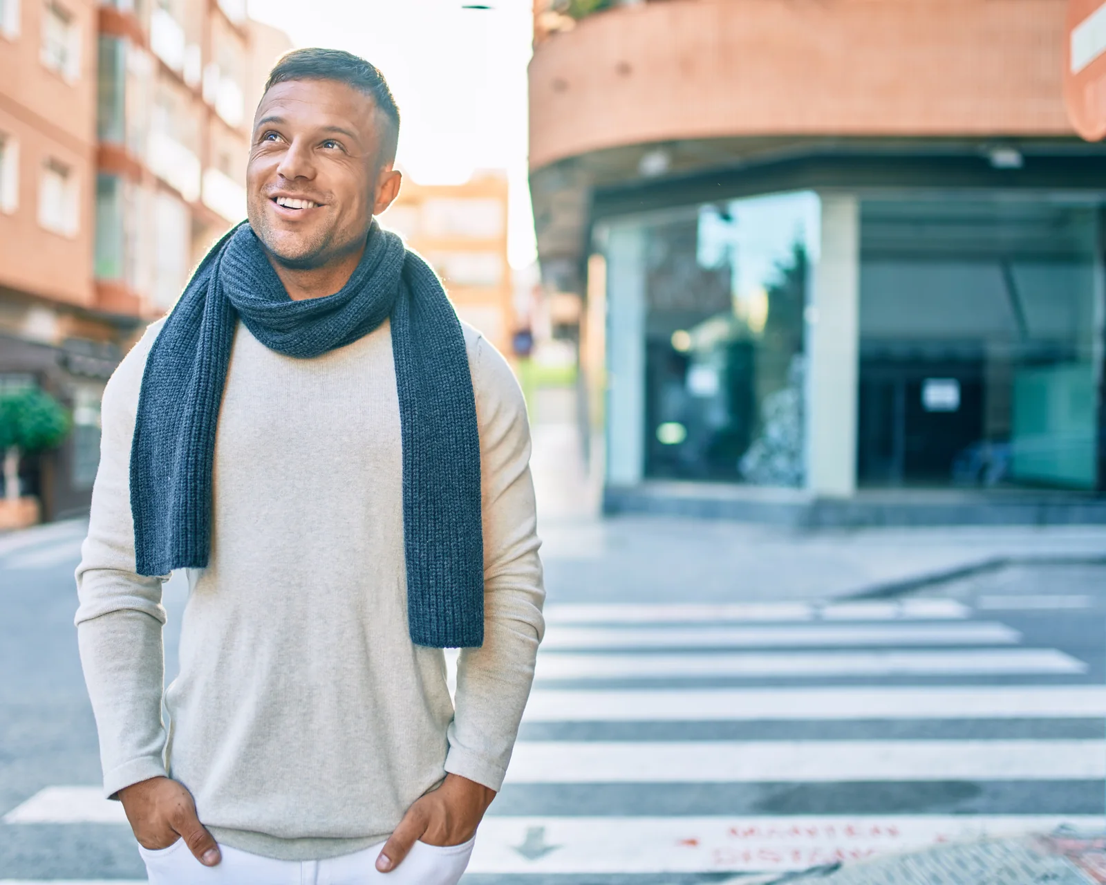 Smiling man in a scarf standing on a city street